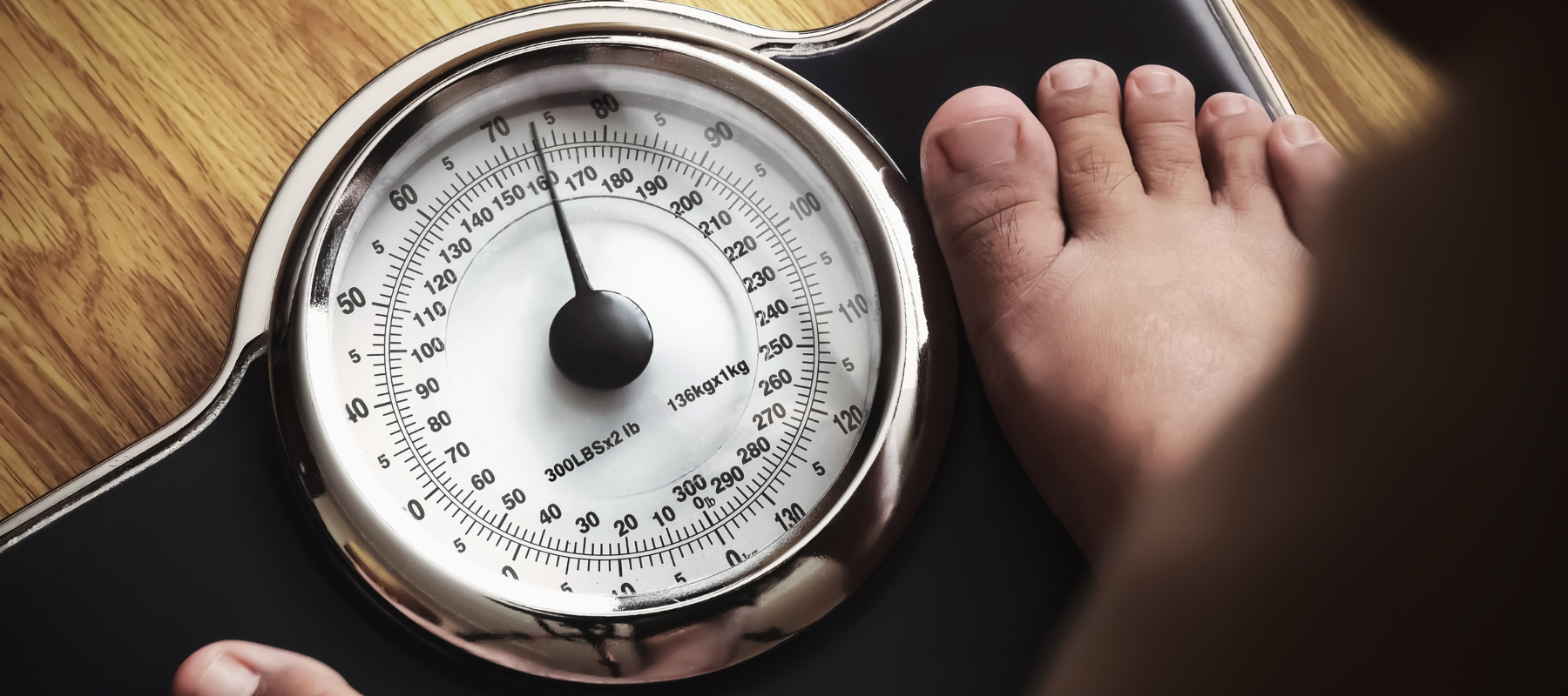 A person with feet on a scale, engaged in the process of checking their weight.